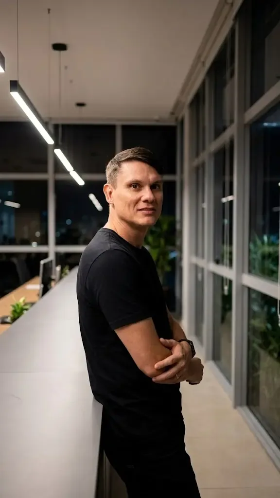Aldo Batista apoiado no parapeito de um escritório à noite